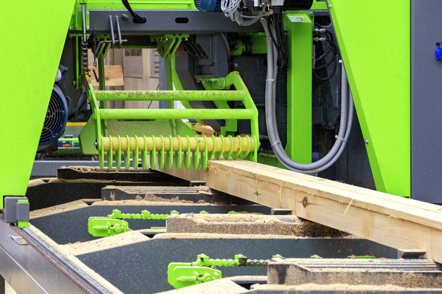 A machine painted a bright green processes logs into boards