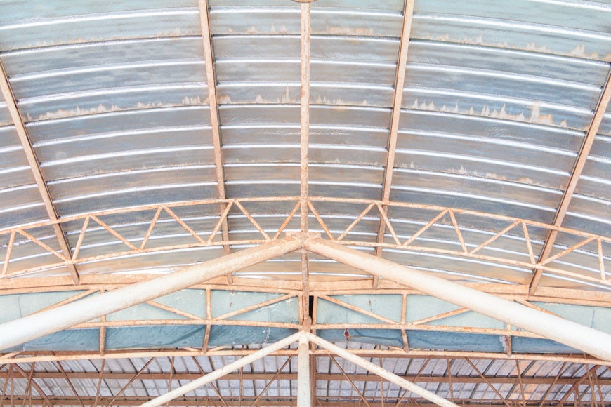 The galvanized metal roof of a building shows white rust where moisture has collected