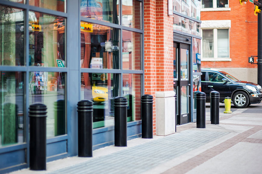 Thick black ringed bollards protect the glass of an electronics store