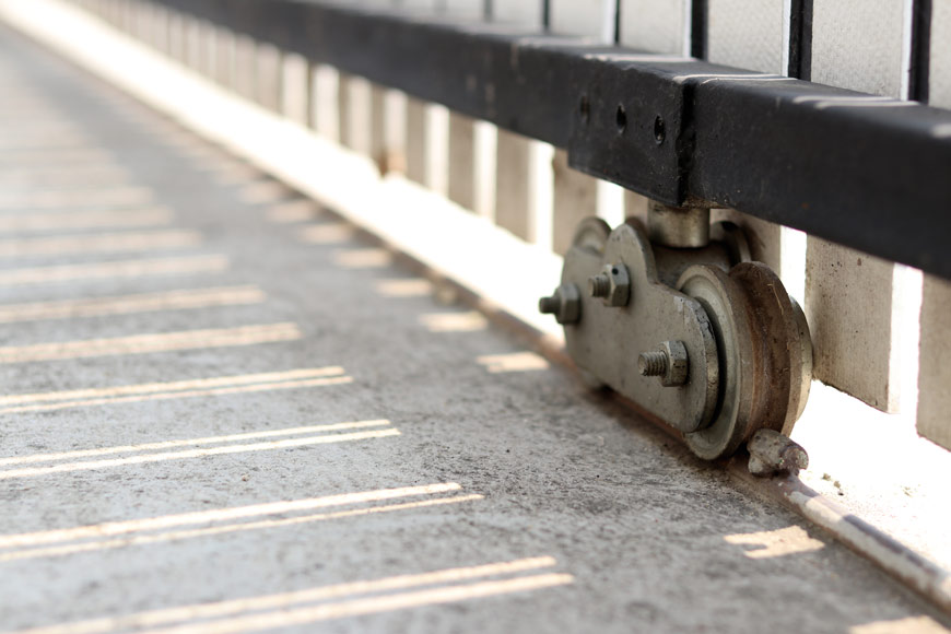 Two wheels attached to a single housing run over painted white rebar.