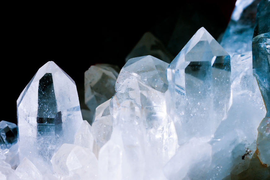 Crystalline plain clear quartz juts up in front of a black background