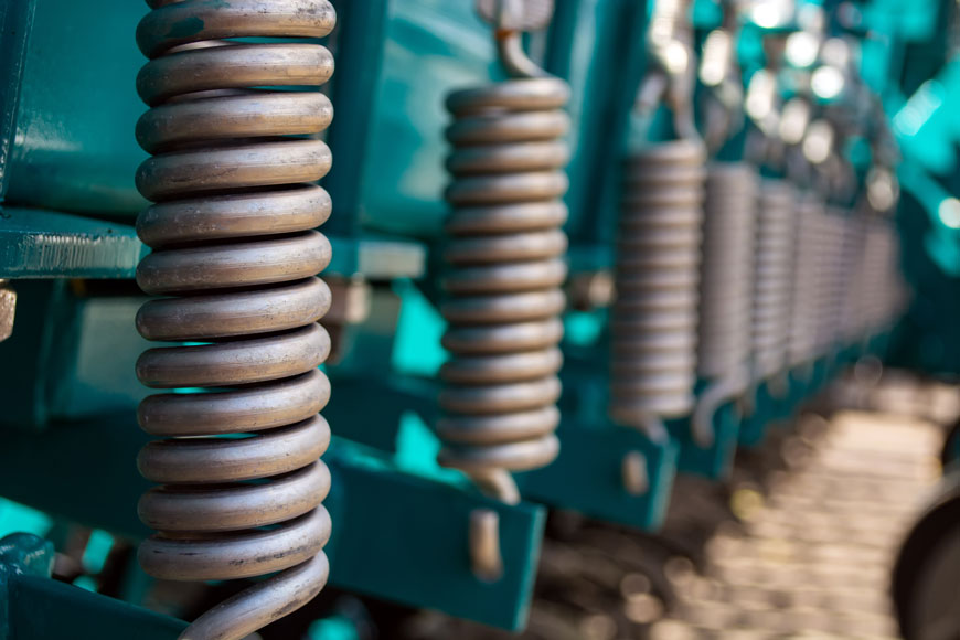 A series of large steel shock springs along a production line.